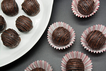 Chocolate candy truffles on black background table, top view. Homemade dark chocolate truffles.