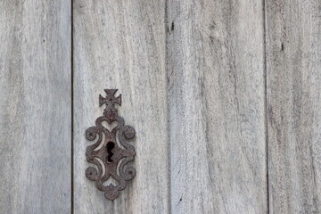Rusty metal keyhole cover plate  on the old wooden door.