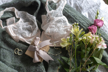 Stylish bouquet, gift and jewelry on sweater with lingerie. Soft feminine image, spring essentials
