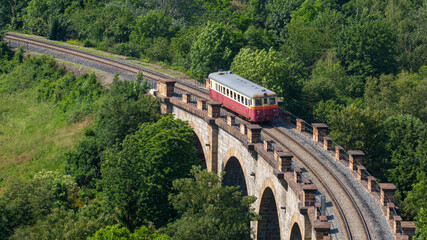 A train passing over an old stone bridge in Prague. The bridge is called Prague Semering
