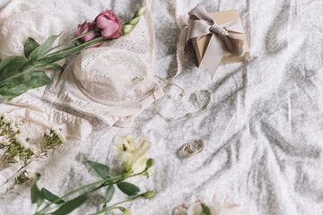 Fototapeta na wymiar Stylish lingerie, gift, modern jewelry and spring bouquet on bed. Soft image. Happy Women's day