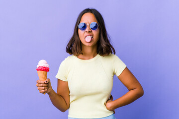 Young mixed race woman eating an ice cream funny and friendly sticking out tongue.