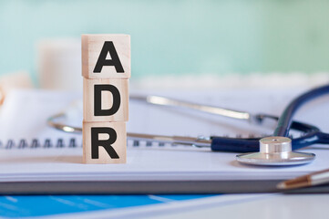 Wooden block form the word ADR with stethoscope on the doctor's desktop. Medical concept.