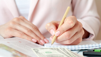 close up of woman hands with calculator counting and taking notes to notebook