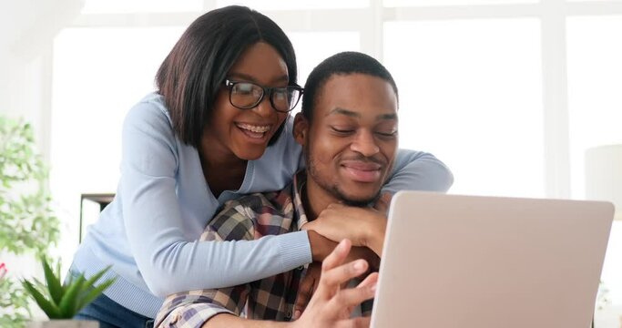 Romantic couple using laptop and discussing at home office