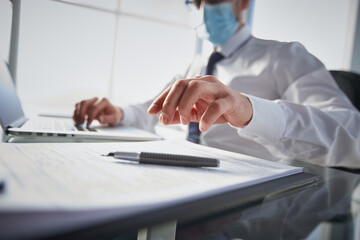 Close up of male hands with laptop computer, notebook and pen taking notes in business office