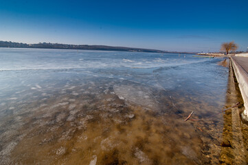 Spring lake and quay. Melting ice on the lake. Warm spring weather