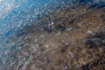 a peg for mooring boats, ice and snow melt on the pond. Fishermen tie boats to pegs. March.