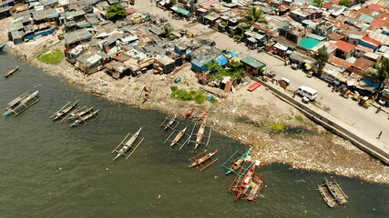 Slums near the port in Manila on the bank of a river polluted with garbage, aerial view.