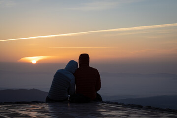 Fototapeta premium Couple watching the amazing sunrise from the top of La Mola Mountain in the Parc natural de Sant Llorenc del Munt i l'Obac, Valles Occidental, Catalonia, Spain. Copy space.