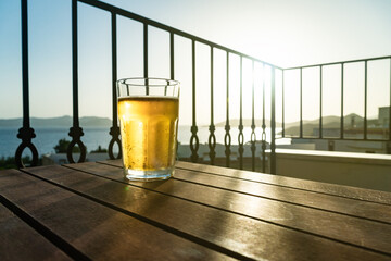 Glass With Beer on table on balcony in on the sunset. Cooling summer drink in hot time, quench...