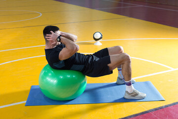 Fototapeta na wymiar Athletic guy in sportswear and fitness tracker doing exercises in gym.