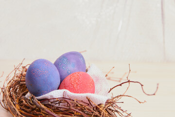 painted easter eggs and a decorative nest made of branches on a wooden table