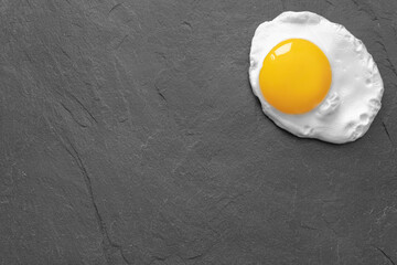 Fried egg on a black stone slate board. Background