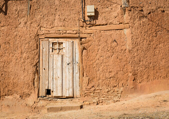 ancient wooden door on an antique wall of a rustic house made of clay