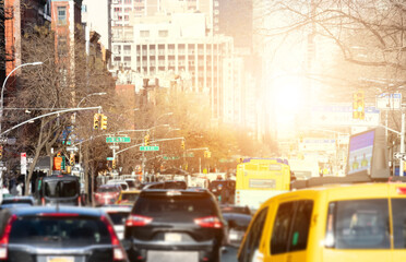 Cars in rush hour traffic along 1st Avenue in Manhattan New York City with sunlight shining between the background