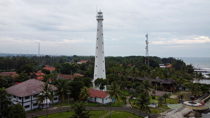 Aerial view of Lighthouse sea rock sunset landscape. Sunset lighthouse scene. At anyer beach with noise cloud and cityscape. 