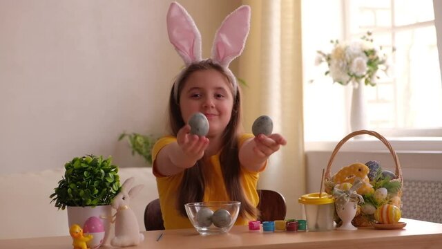 funny happy child girl playing with easter eggs at home