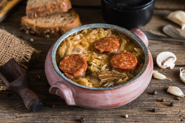 Christmas cabbage soup in ceramic bowl on natural wooden background.