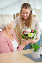 woman giving giving grandma a bunch of flowers