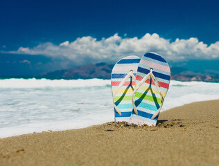 Obraz premium Colored sandals stuck in the sand on the beach