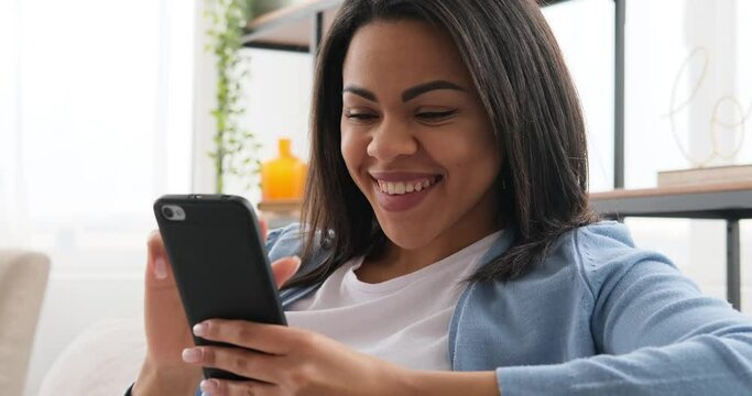 Woman amazed on receiving good news using mobile phone at home