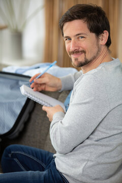 handsome bearded man packing stuff to a trip check list