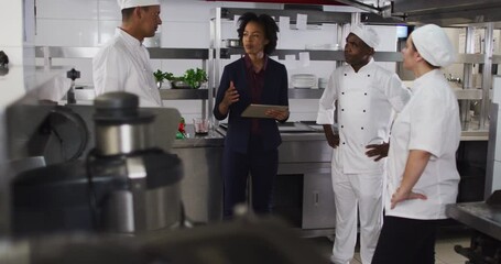 African american female manager using tablet and talking with chefs
