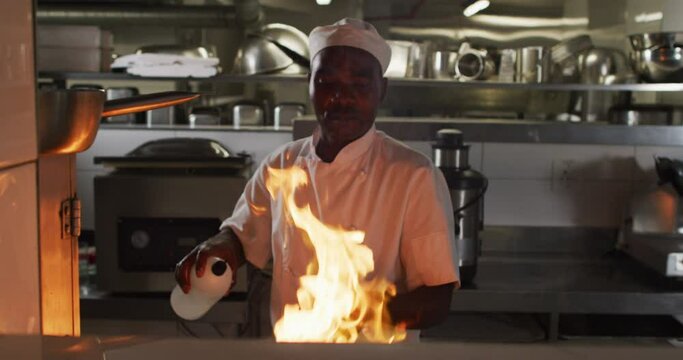 African american male chef frying in pan in restaurant kitchen