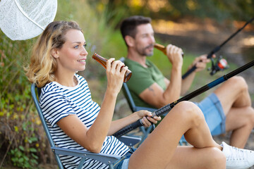 couple having a beer while sport fishing on the lakeside