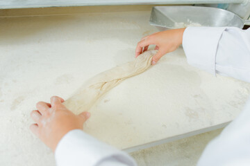 hands are rolling a bagette