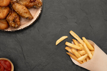 Fried fries with tomato sauce, grilled wings and nuggets