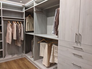 walk in closet with shirts and pants hanging up on hangers and shoes on the shelving