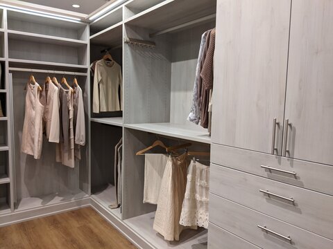 Walk In Closet With Shirts And Pants Hanging Up On Hangers And Shoes On The Shelving