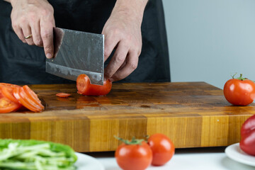 Close up of Chef cook hands chopping vegetables for traditional cuisine with Japanese knife. Professional chef cutting tomato on wooden board.