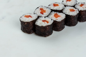 Sushi rolls prepared by professional asian chef with traditional Japanese ingredients. Salmon, rice, vegetables, sesame seeds. 