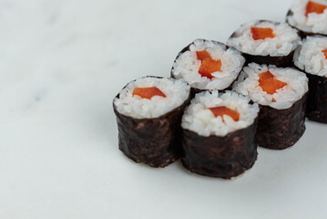 Sushi rolls prepared by professional asian chef with traditional Japanese ingredients. Salmon, rice, vegetables, sesame seeds. 