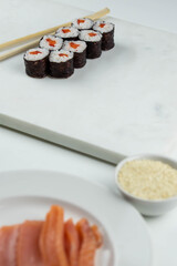 Sushi rolls prepared by professional asian chef with traditional Japanese ingredients. Salmon, rice, vegetables, sesame seeds. Sushi cooking and making concept