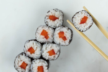 Sushi rolls prepared by professional asian chef with traditional Japanese ingredients. Salmon, rice, vegetables, sesame seeds. 