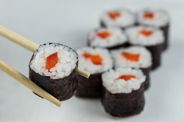 Sushi rolls prepared by professional asian chef with traditional Japanese ingredients. Salmon, rice, vegetables, sesame seeds. 