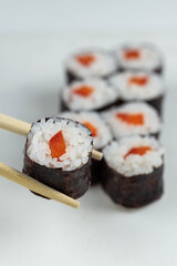 Sushi rolls prepared by professional asian chef with traditional Japanese ingredients. Salmon, rice, vegetables, sesame seeds. 