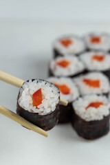 Sushi rolls prepared by professional asian chef with traditional Japanese ingredients. Salmon, rice, vegetables, sesame seeds. 