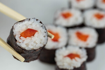 Sushi rolls prepared by professional asian chef with traditional Japanese ingredients. Salmon, rice, vegetables, sesame seeds. 