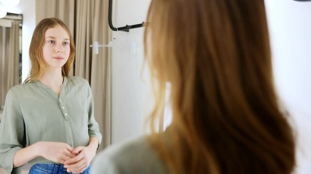 Tween girl standing in fitting room in clothing store.