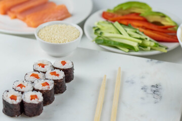 Sushi rolls prepared by professional asian chef with traditional Japanese ingredients. Salmon, rice, vegetables, sesame seeds. Sushi cooking and making concept