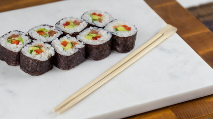 Sushi rolls prepared by professional asian chef with traditional Japanese ingredients. Salmon, rice, vegetables, sesame seeds. 