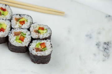 Sushi rolls prepared by professional asian chef with traditional Japanese ingredients. Salmon, rice, vegetables, sesame seeds. 