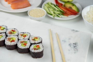 Sushi rolls prepared by professional asian chef with traditional Japanese ingredients. Salmon, rice, vegetables, sesame seeds.  Sushi cooking and making concept