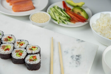 Sushi rolls prepared by professional asian chef with traditional Japanese ingredients. Salmon, rice, vegetables, sesame seeds.  Sushi cooking and making concept