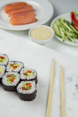 Sushi rolls prepared by professional asian chef with traditional Japanese ingredients. Salmon, rice, vegetables, sesame seeds.  Sushi cooking and making concept